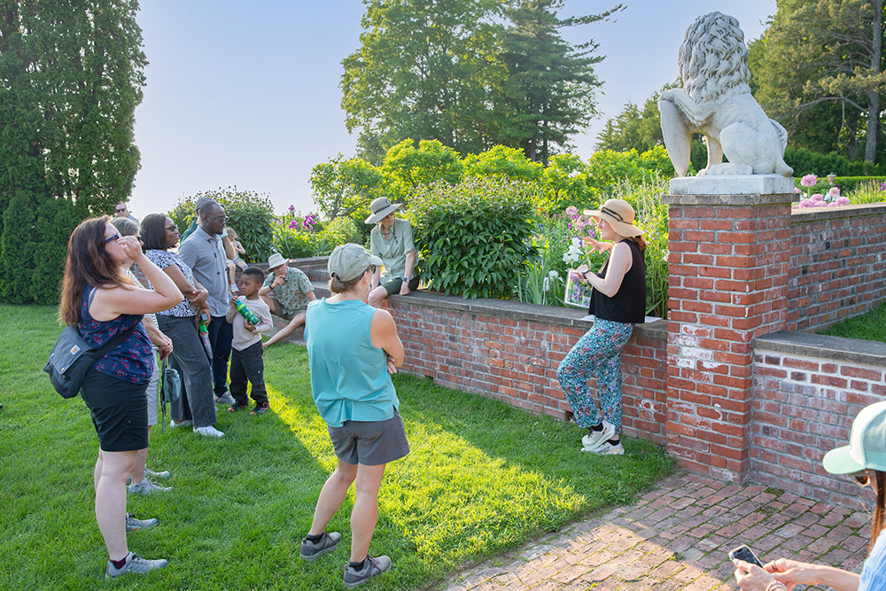 small group of people standing around woman in the Inn Formal Gardens in early June