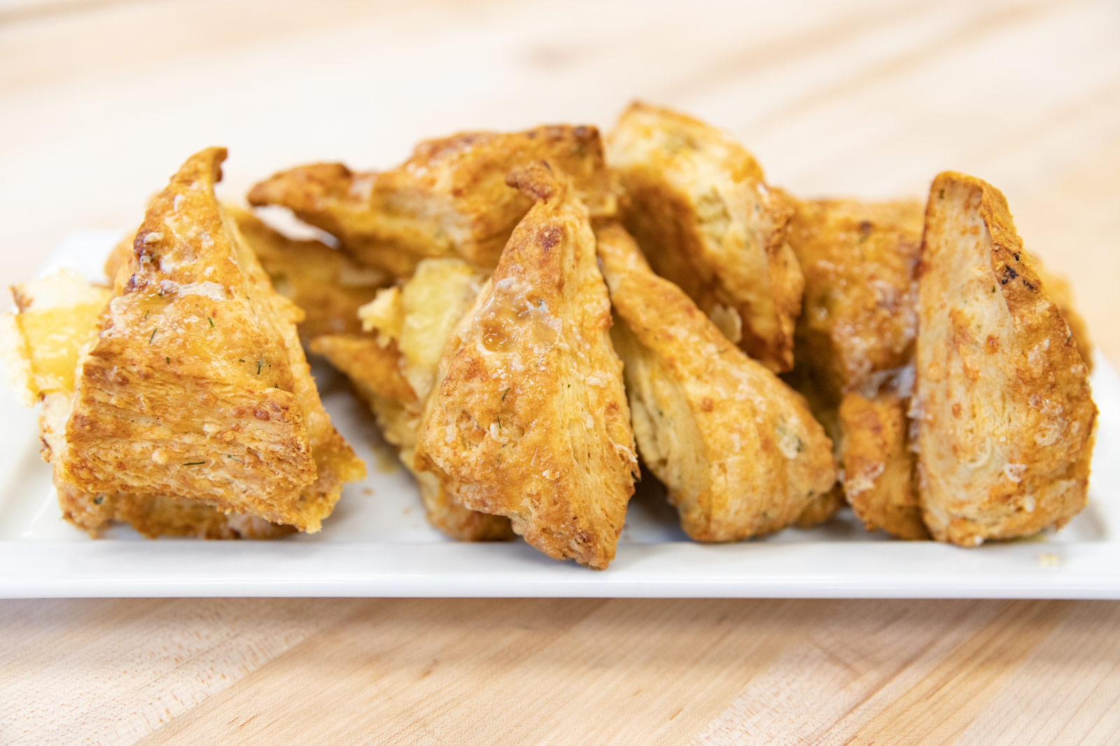 A plate of freshly baked cheddar scones is displayed on a  white plate.
