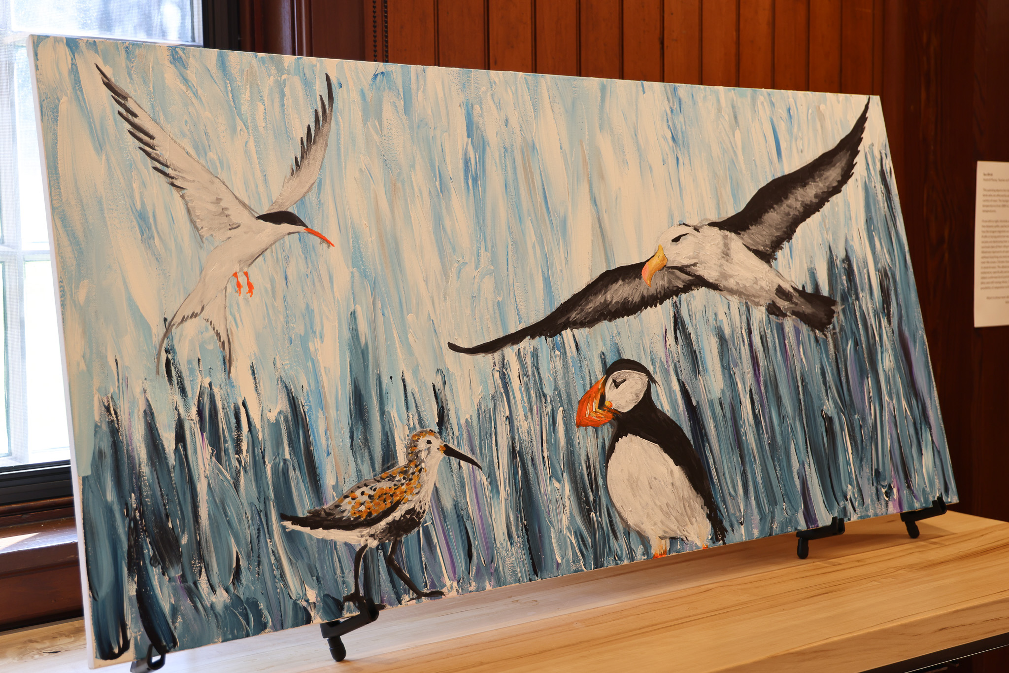 A large painting depicting seabirds against a blue and white background