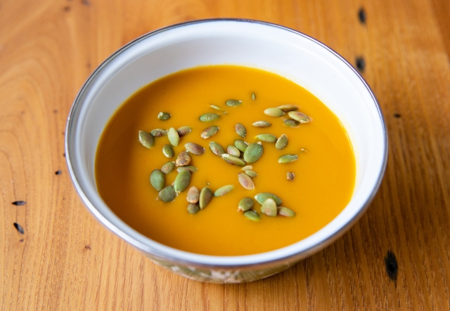 A bowl of spiced sweet potato soup garnished with pepitas