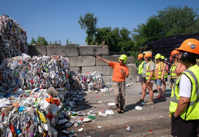 A group of people tour an outdoor recycling facility